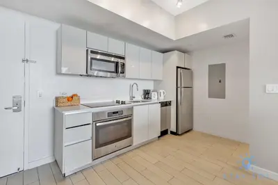a kitchen with white cabinets and a stainless steel refrigerator at Amazing View - Pool - Gym - 2 Bedrooms in Hallandale Beach