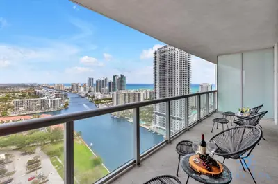 a balcony with chairs and a table and a view of the water at Amazing View - Pool - Gym - 2 Bedrooms in Hallandale Beach