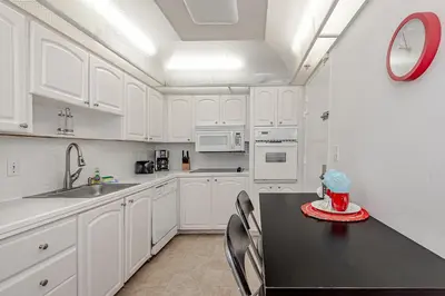 a kitchen with white cabinets and a table with a cake on it at Hollywood on The Beach in Hollywood