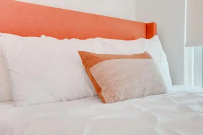 a bed with white pillows and an orange headboard at Stylish 1BR APT with Ocean and City view,pool,parking in Miami