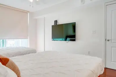 a white bedroom with two beds and a tv on the wall at Stylish 1BR APT with Ocean and City view,pool,parking in Miami