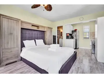 a bedroom with a large white bed and a refrigerator at Chic Studio Apartment in Hollywood Beach in Hollywood
