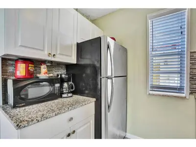 a kitchen with a stainless steel refrigerator and white cabinets at Chic Studio Apartment in Hollywood Beach in Hollywood