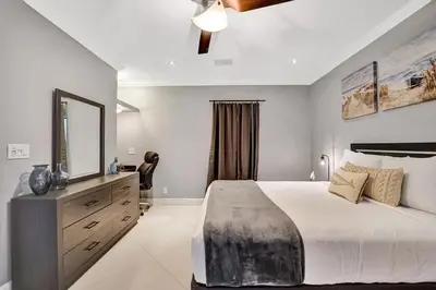 a bedroom with a large bed with a mirror and a dresser at Beach Isles Modern 1BR Waterfront Apartment with Patio in Fort Lauderdale