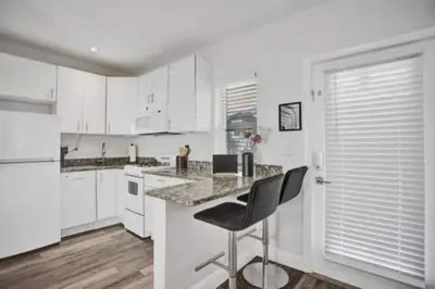 a kitchen with white cabinets and a table and chairs at Beach Isles Modern Studio Apartment in Fort Lauderdale in Fort Lauderdale