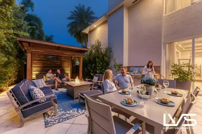 a group of people sitting around a table on a patio at Poinciana-LuxeHome Wlk2Beach HeatedPool HotTub in Fort Lauderdale