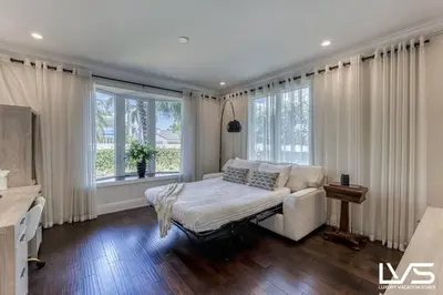 a living room with a couch and windows at Poinciana-LuxeHome Wlk2Beach HeatedPool HotTub in Fort Lauderdale