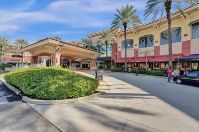a street in front of a shopping mall with palm trees at Beach Isles Modern 1BR in Fort Lauderdale with Patio in Fort Lauderdale
