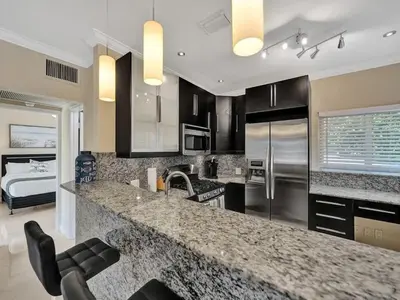 a kitchen with a counter and a sink and a room at Beach Isles Modern 1BR in Fort Lauderdale with Patio in Fort Lauderdale