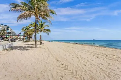 a sandy beach with palm trees and the ocean at Rustic Retreats Modern 1BR For 4 Guests Minutes From Las Olas in Fort Lauderdale