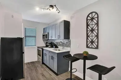 a kitchen with a black refrigerator and a table at Rustic Retreats Modern 1BR For 4 Guests Minutes From Las Olas in Fort Lauderdale