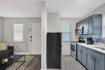a kitchen with blue cabinets and a black refrigerator at Rustic Retreats Spacious 1BR For 4 guests In The Heart of Fort Lauderdale in Fort Lauderdale