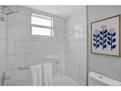 a white bathroom with a shower and a window at Rustic Retreats Cozy 1BR for 4 guests minutes from Las Olas in Fort Lauderdale