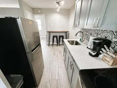 a kitchen with a stainless steel refrigerator and a table at Rustic Retreats Beachy 1BR for 4 guests in the heart of Fort Lauderdale in Fort Lauderdale
