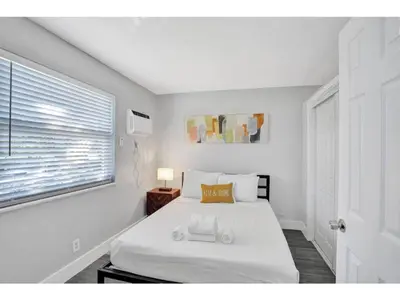 a bedroom with a white bed and a window at Rustic Retreats Cozy 1BR For 4 Guests Minutes From Las Olas in Fort Lauderdale