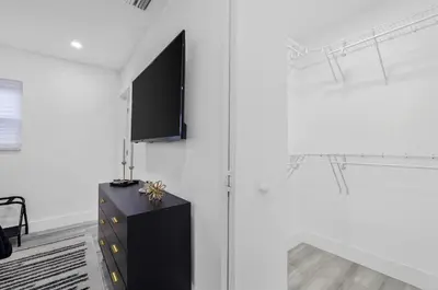 a room with a black dresser and a tv on a wall at Modern villa in Design District ! in Miami