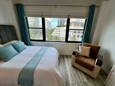 a bedroom with a bed and a chair and a window at Directly on the Beach with Pool & Parking in Miami Beach