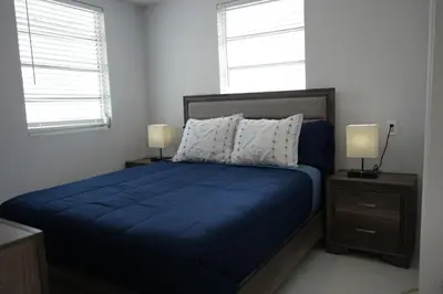 a bedroom with a blue bed with two night stands and two windows at Charming two bedroom apartment. in Miami