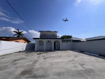a plane flying over a building with a fence at Charming two bedroom apartment. in Miami