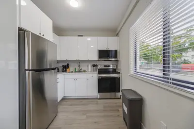 a kitchen with white cabinets and a stainless steel refrigerator at Prime Location Apt on Calle Ocho in Little Havana in Miami