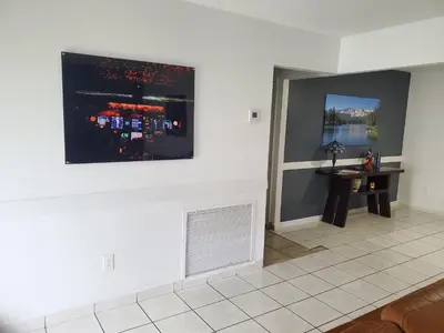 a living room with a table and a painting on the wall at Cozy family home in quiet area, nice garden views. in Tamiami