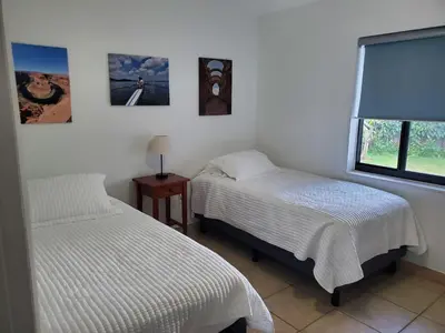 two twin beds in a room with a window at Cozy family home in quiet area, nice garden views. in Tamiami