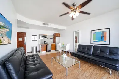 a living room with a black leather couch and a table at Strand Ocean Drive Suites in Miami Beach