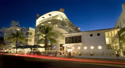 a large white building with palm trees in front of it at Strand Ocean Drive Suites in Miami Beach