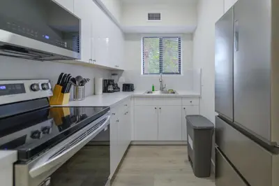 a kitchen with white cabinets and a stainless steel refrigerator at Apartment in Calle Ocho a Slice of Little Havana in Miami