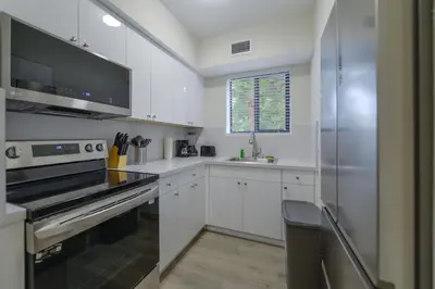 a kitchen with white cabinets and a stainless steel refrigerator at Apartment in Calle Ocho a Slice of Little Havana in Miami
