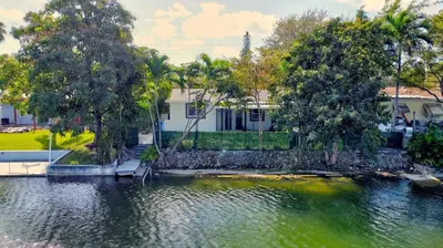 a house sitting on top of a body of water at Hallandale Collection - Renovated Professional Design & Lake View in Ro-Len Lake Gardens