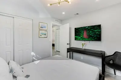 a white bedroom with a bed and a desk at Hallandale Collection - Renovated Professional Design & Lake View in Ro-Len Lake Gardens