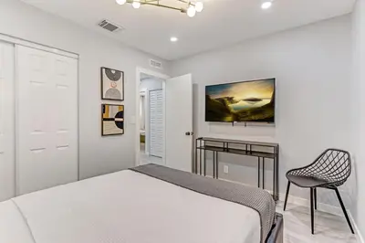 a white bedroom with a bed and a chair at Hallandale Collection - Renovated Professional Design & Lake View in Ro-Len Lake Gardens