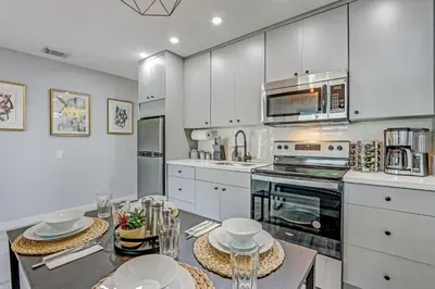a kitchen with white cabinets and a table with dishes at Hallandale Collection - Renovated Professional Design & Lake View in Ro-Len Lake Gardens