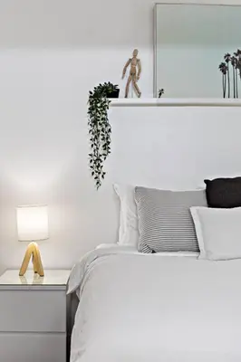 a white bedroom with a bed and a plant on a shelf at Charming Apartment near Las Olas Blvd in Fort Lauderdale