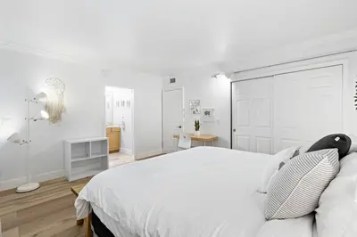 a white bedroom with a large white bed with white walls at Charming Apartment near Las Olas Blvd in Fort Lauderdale