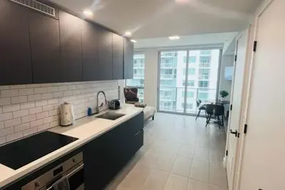 a kitchen with black cabinets and a living room at Huge Studio POOL & GYM - Explore Miami's Heat in Miami