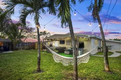 a house with a hammock in a yard with palm trees at 7-Person Luxury Spa, Fenced Paradise, Beach Vibes in Pembroke Pines