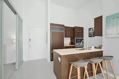 a kitchen with a sink and two stools in it at 28th Floor Icon Brickell Penthouse with City Views in Miami