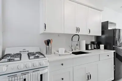 a white kitchen with a stove and a refrigerator at North Shore Oasis - Steps to Miami Beach Bliss in Miami Beach