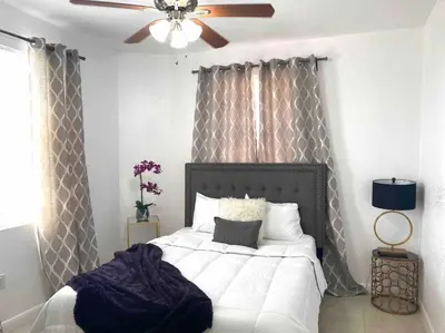 a bedroom with a white bed with a ceiling fan at ZION Miami Design District 2 Bedroom amongst the trees! in Miami