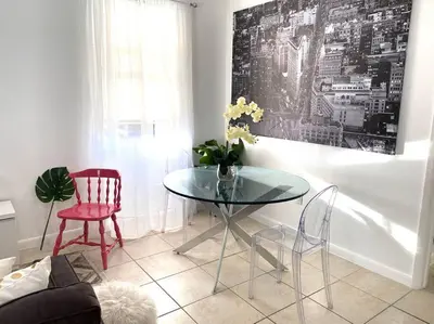 a dining room with a glass table and a red chair at ZION Miami Design District 2 Bedroom amongst the trees! in Miami