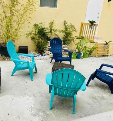 a group of blue chairs sitting next to a building at ZION Miami Design District 2 Bedroom amongst the trees! in Miami
