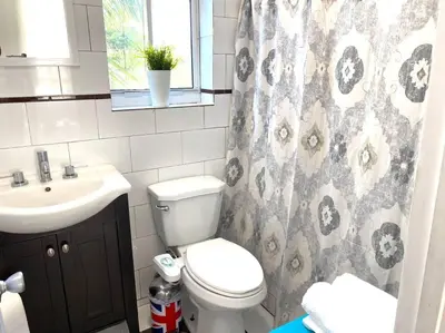 a bathroom with a toilet and a sink and a shower curtain at ZION Miami Design District 2 Bedroom amongst the trees! in Miami