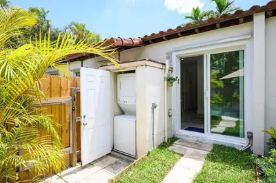 a small white house with a door and a yard at Bright & Comfortable Apt in Victoria Park in Fort Lauderdale