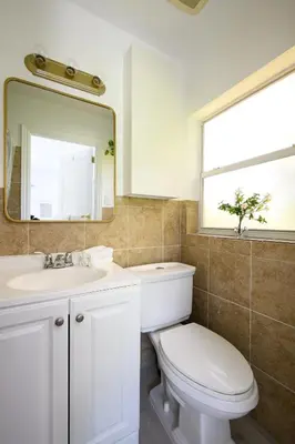 a bathroom with a toilet and a sink and a mirror at Bright & Comfortable Apt in Victoria Park in Fort Lauderdale