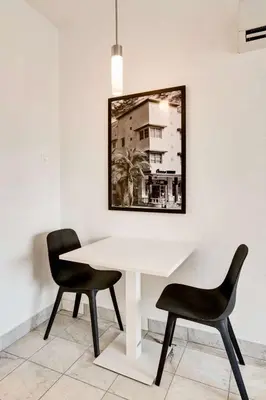 a white table with two chairs and a picture on the wall at Best location by the Beach ! Free WiFi - TV - All amenities 103 in Miami Beach