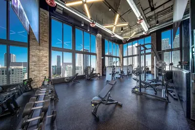 a gym with treadmills and machines in a large room with windows at Sentral Alea Miami in Miami