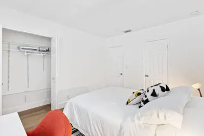 a white bedroom with a bed and a red chair at Lovely 2 BR condo with free parking on premises in Fort Lauderdale