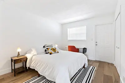 a white bedroom with a bed and a chair at Lovely 2 BR condo with free parking on premises in Fort Lauderdale